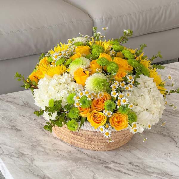 Yellow and white flower arrangement in a woven basket