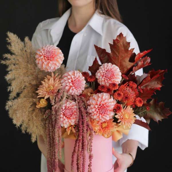 Pink and peach floral arrangement in a round pink box