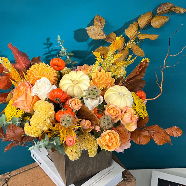 Autumn floral arrangement with pumpkins and orange roses in a square container