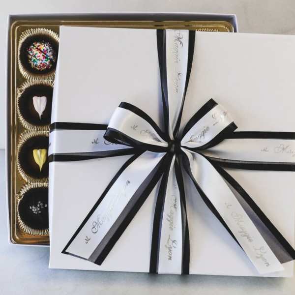 Gift box with black ribbon over a tray of assorted chocolates
