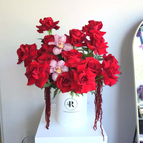 Hatbox arrangement of red roses with pink orchids in a white cylinder container