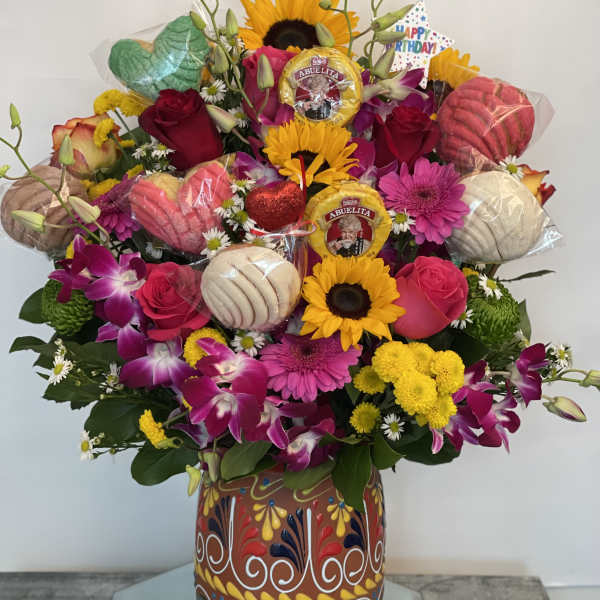 Colorful birthday bouquet with roses, sunflowers, orchids, and chocolates in a painted vase