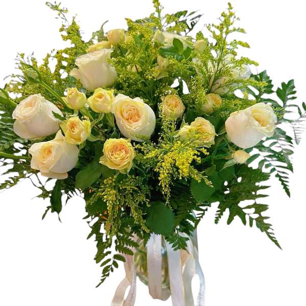 Bouquet of cream roses with yellow filler flowers in a glass vase