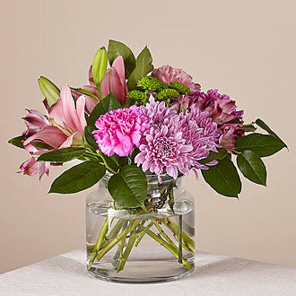Pink and purple flowers arranged in a clear glass vase