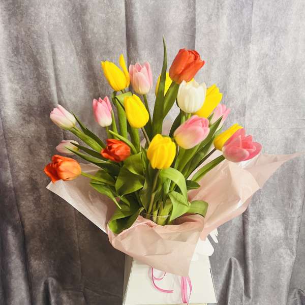 Bouquet of multicolored tulips wrapped in pink paper