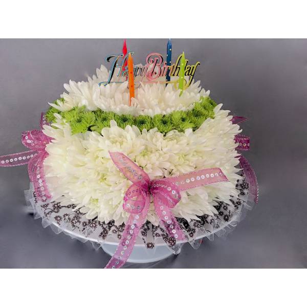 White chrysanthemum cake with candles and a birthday topper