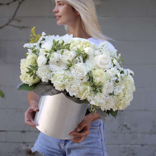 Woman holding a large white floral arrangement in a silver box
