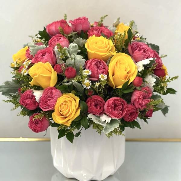Pink and yellow rose bouquet in a white vase