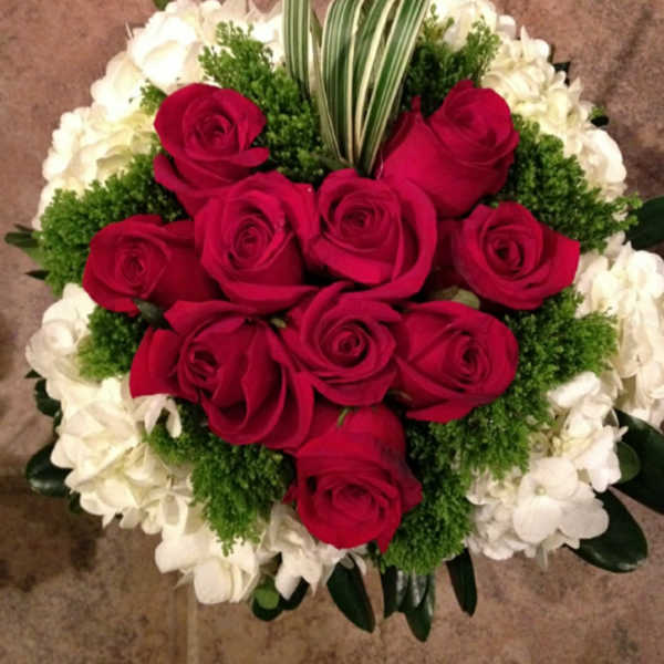 Red roses arranged with white flowers and greenery