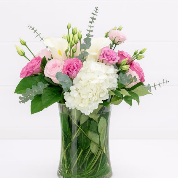 Pink and white flowers arranged in a clear glass vase