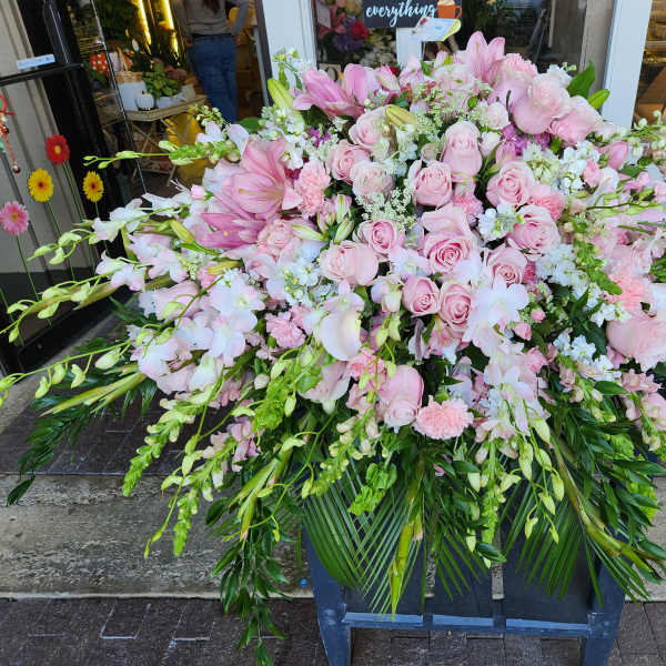 Large pink floral arrangement with roses and orchids in a stand