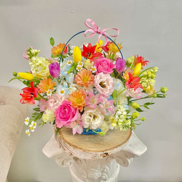 Colorful mixed flower basket with a pink ribbon handle