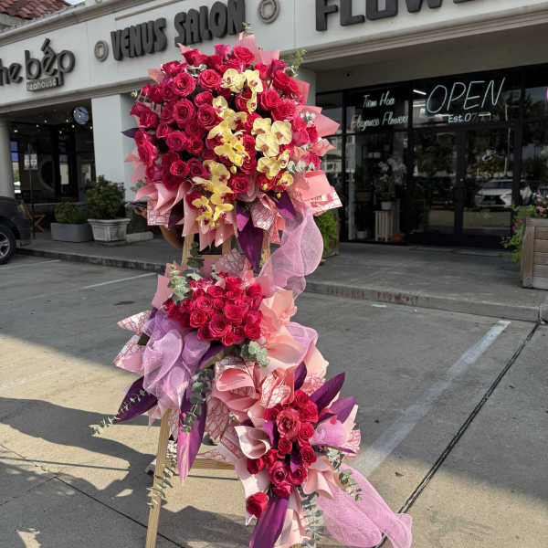 Tall standing floral arrangement with hot pink roses and yellow orchids