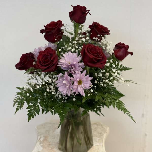Bouquet of red roses and light purple daisies in a glass vase