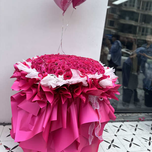 Large pink rose arrangement with heart balloons and layered pink wrapping