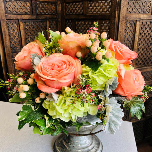 Peach roses and green hydrangeas in a silver pedestal vase