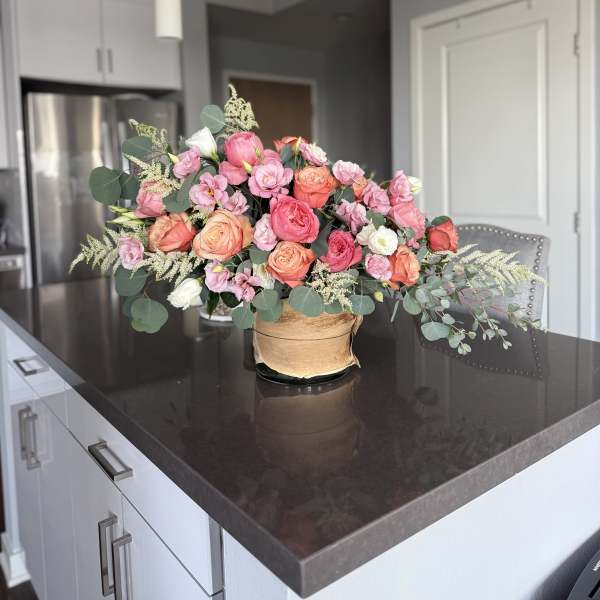 Pink and peach rose bouquet in a low vase on a kitchen counter