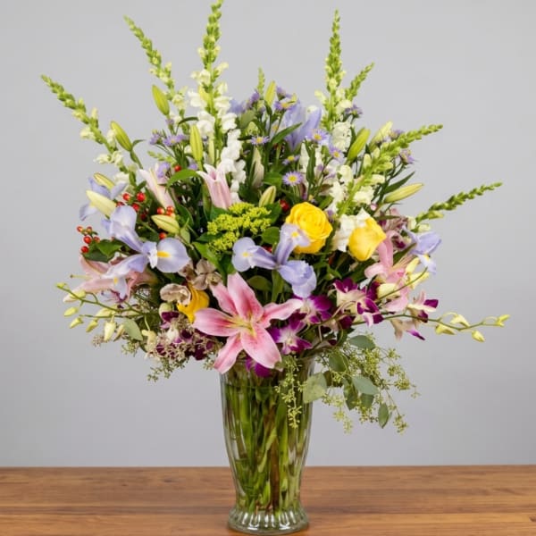 Mixed bouquet of lilies, roses, and snapdragons in a clear glass vase
