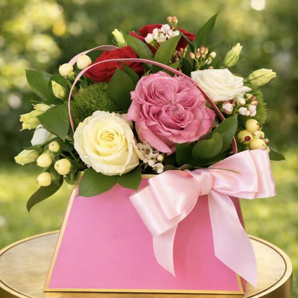 Pink and white roses in a pink gift bag with a ribbon
