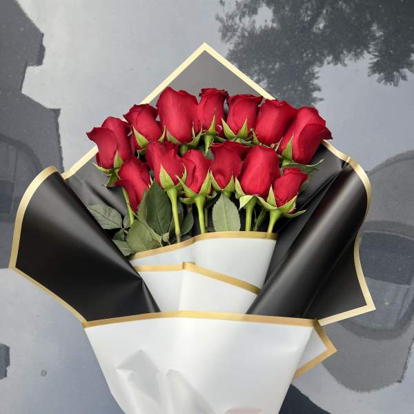 Bouquet of red roses wrapped in black and white paper with a pink ribbon