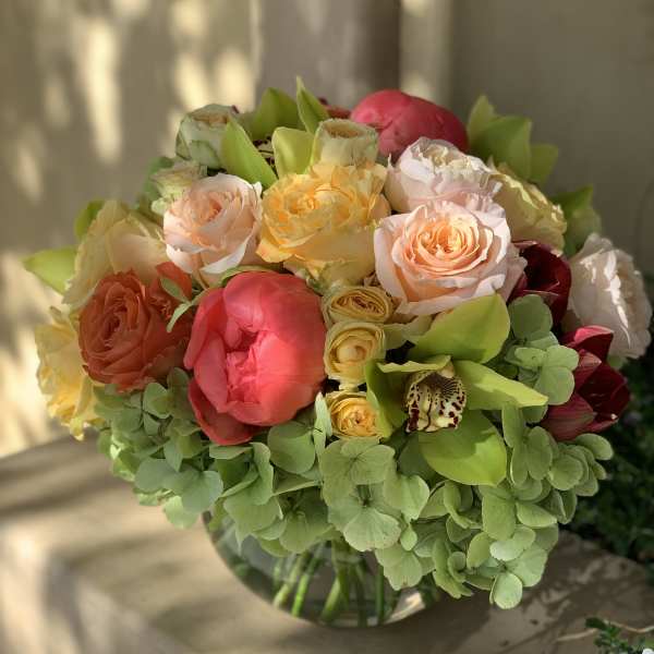 Mixed bouquet of peach, pink, and yellow flowers in a glass vase