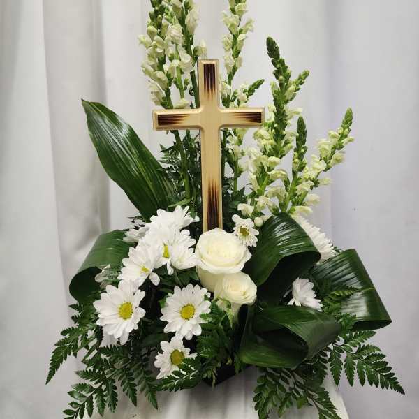 White floral arrangement with a wooden cross and daisies