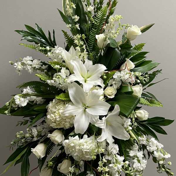 Tall white floral spray with lilies and roses on a stand