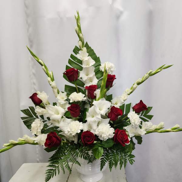 Red roses and white gladiolus arranged in a white vase
