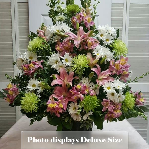 Tall arrangement of pink lilies, white daisies, and green mums in a dark vase