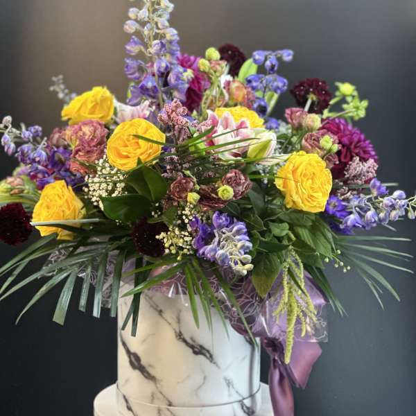 Mixed bouquet in a marble-patterned box with yellow and purple flowers