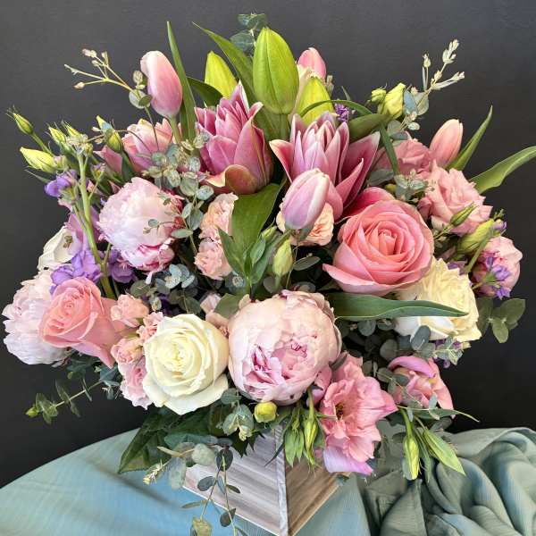Pink and white bouquet with roses, tulips, and peonies in a square vase