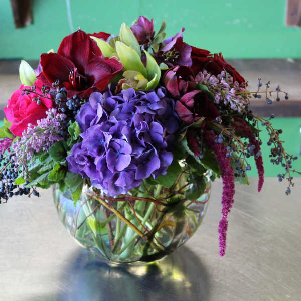 Mixed bouquet of purple, red, and pink flowers in a glass vase