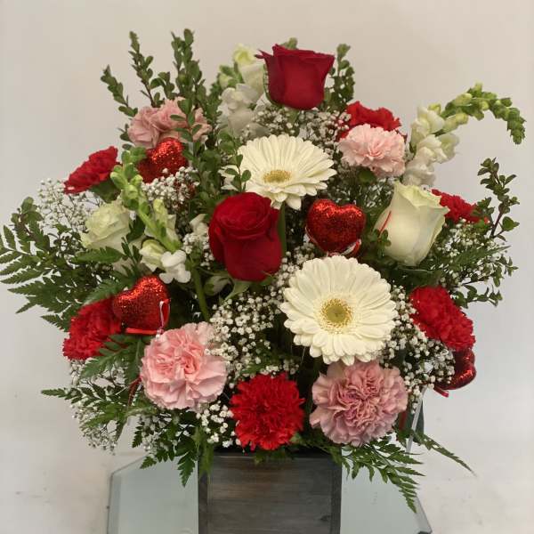 Mixed bouquet of red and white flowers in a wooden box with red heart picks