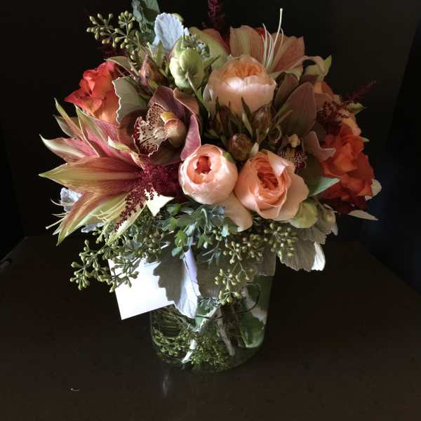 Bouquet of peach and coral flowers in a glass vase