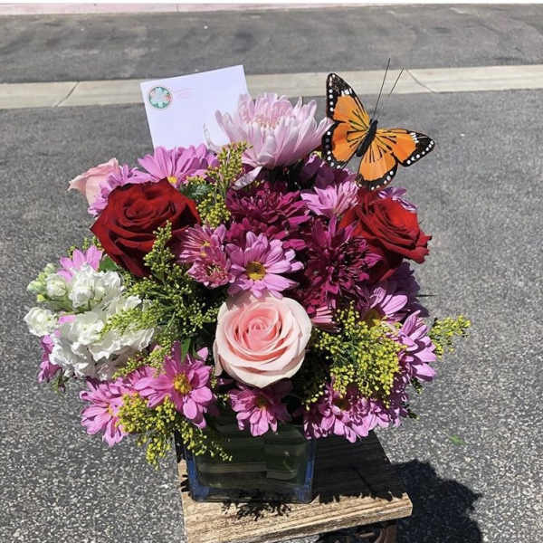 Bouquet of pink and red flowers in a glass vase with a butterfly pick