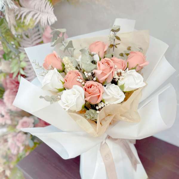 Bouquet of blush and white roses wrapped in white paper