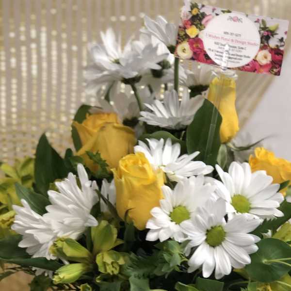 Yellow roses and white daisies in a clear glass vase