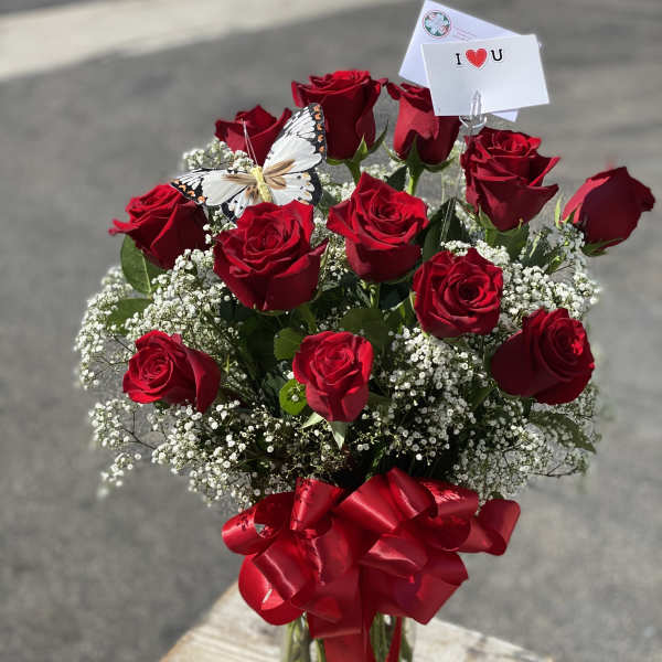 Red roses in a glass vase with baby's breath and a red ribbon