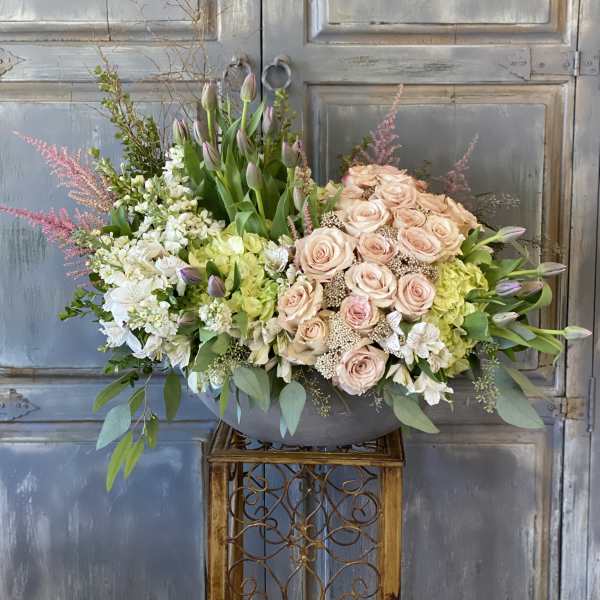 Large pastel floral arrangement with roses, tulips, and hydrangeas in a gray bowl