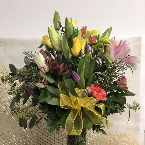 Mixed bouquet of lilies and roses in a glass vase with a yellow bow