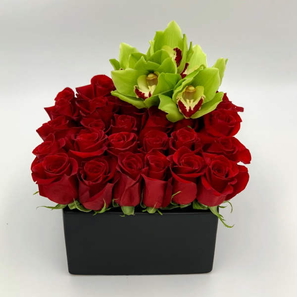 Red roses with green orchids in a black rectangular box
