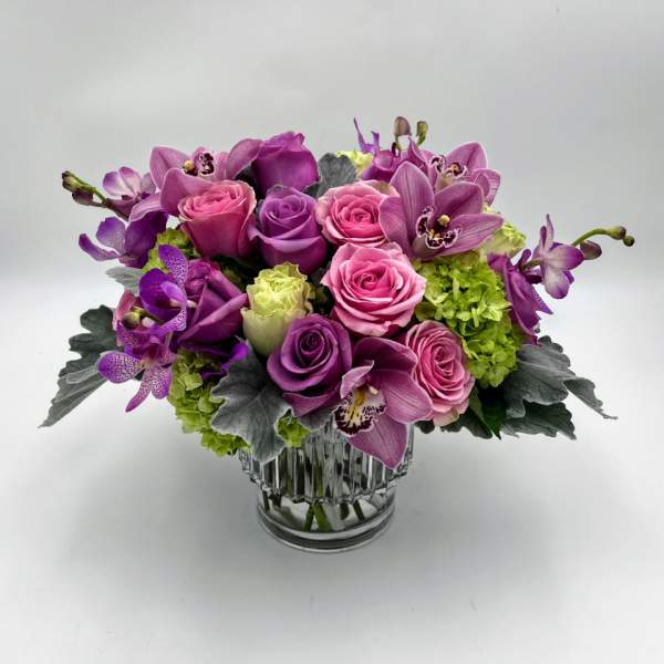 Pink and purple flower arrangement in a clear glass vase