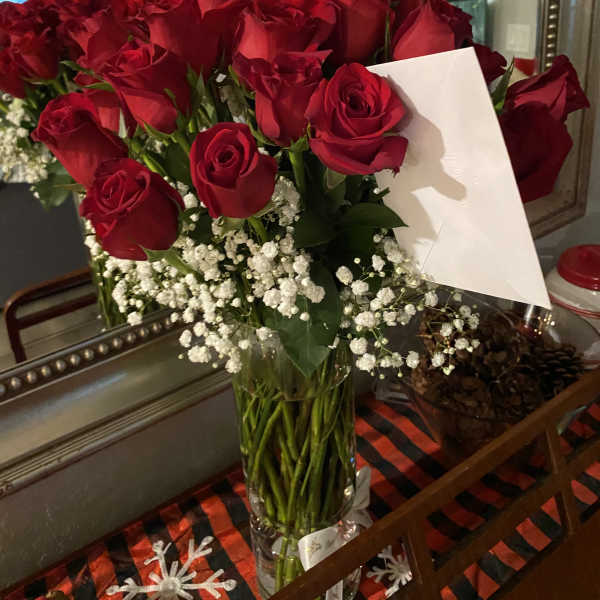 Bouquet of red roses with baby's breath in a clear glass vase