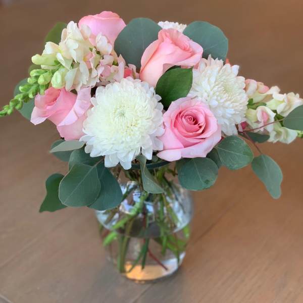 Pink roses and white mums in a glass vase with eucalyptus