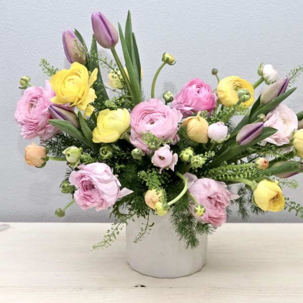 Pink and yellow ranunculus bouquet in a white vase