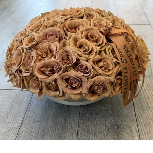 Round bouquet of tan roses with an orange ribbon