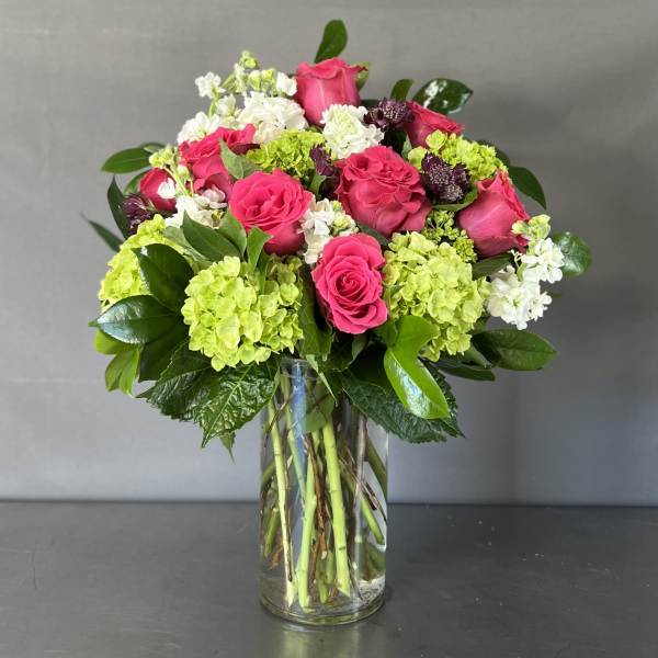 Pink roses and green hydrangeas arranged in a clear glass vase.