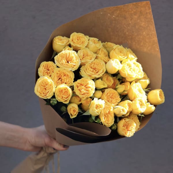 Bouquet of yellow roses wrapped in brown paper