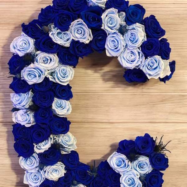 Heart-shaped arrangement of blue and white roses on a wooden surface