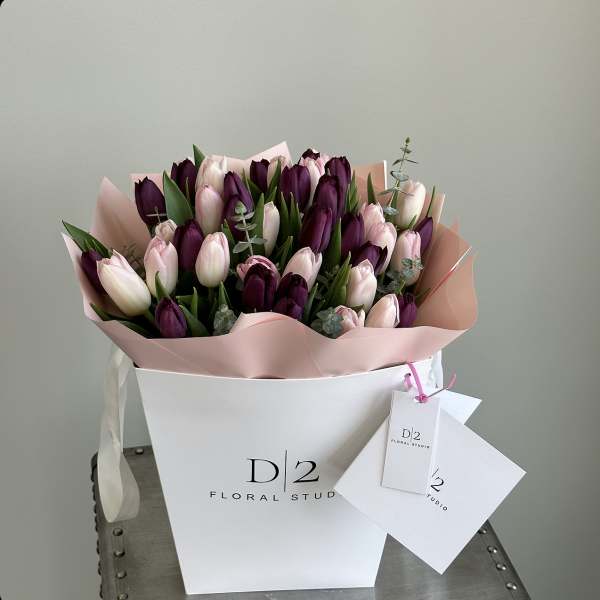 Bouquet of pink and deep purple tulips in a white box